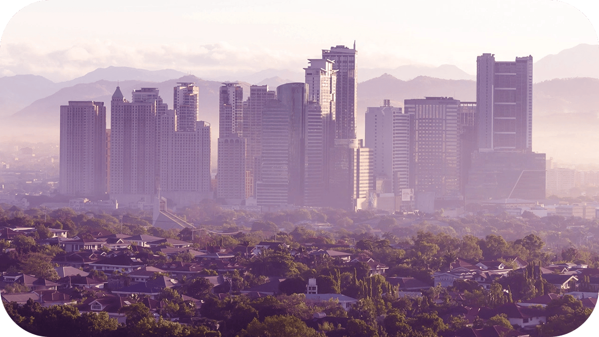 A city with houses & greenery in the foreground, with skyscrapers & a mountain in the background.